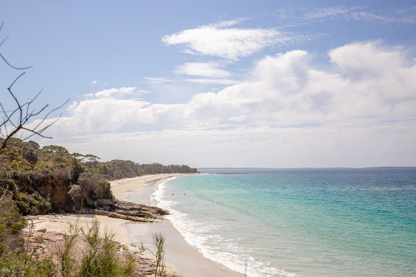 A secluded beach with pristine blue water and surrounding bushland. 