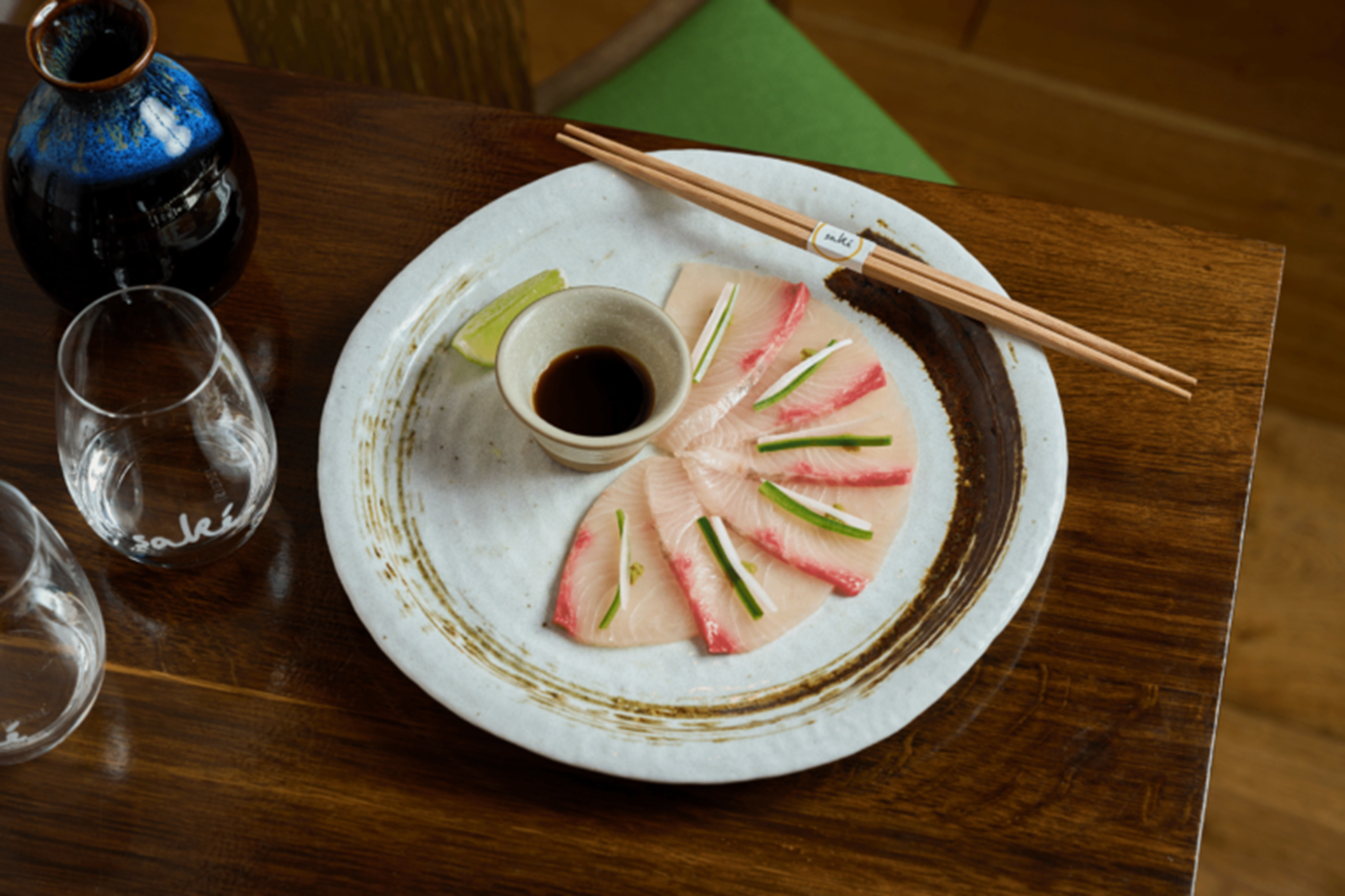 A fan o sashimi atop a white plate sitting on a wooden table 