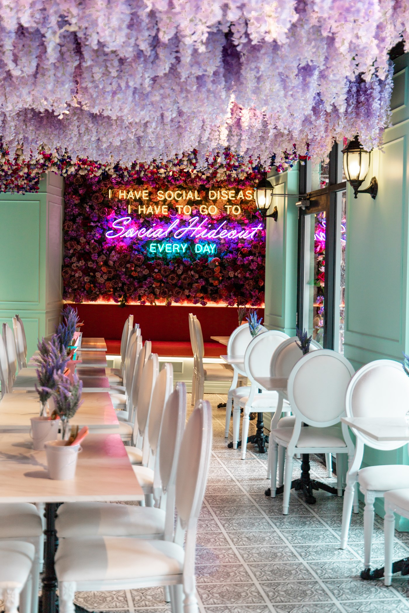 Colourful dining room with hanging purple wisteria and bright neon signs at Social Hideout Parramatta