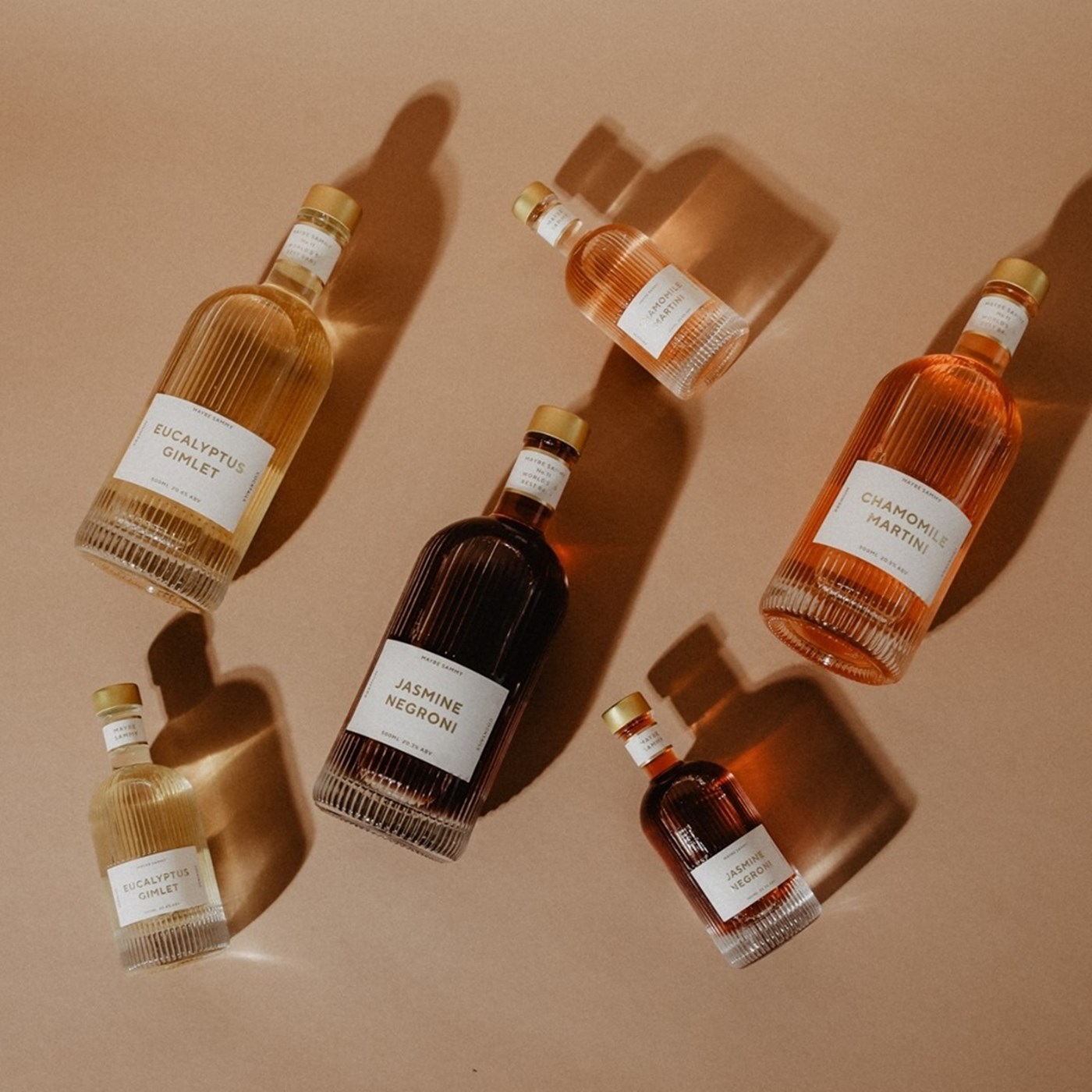 An array of mini and full-sized bottles cocktails from Maybe Sammy against a peach background. 