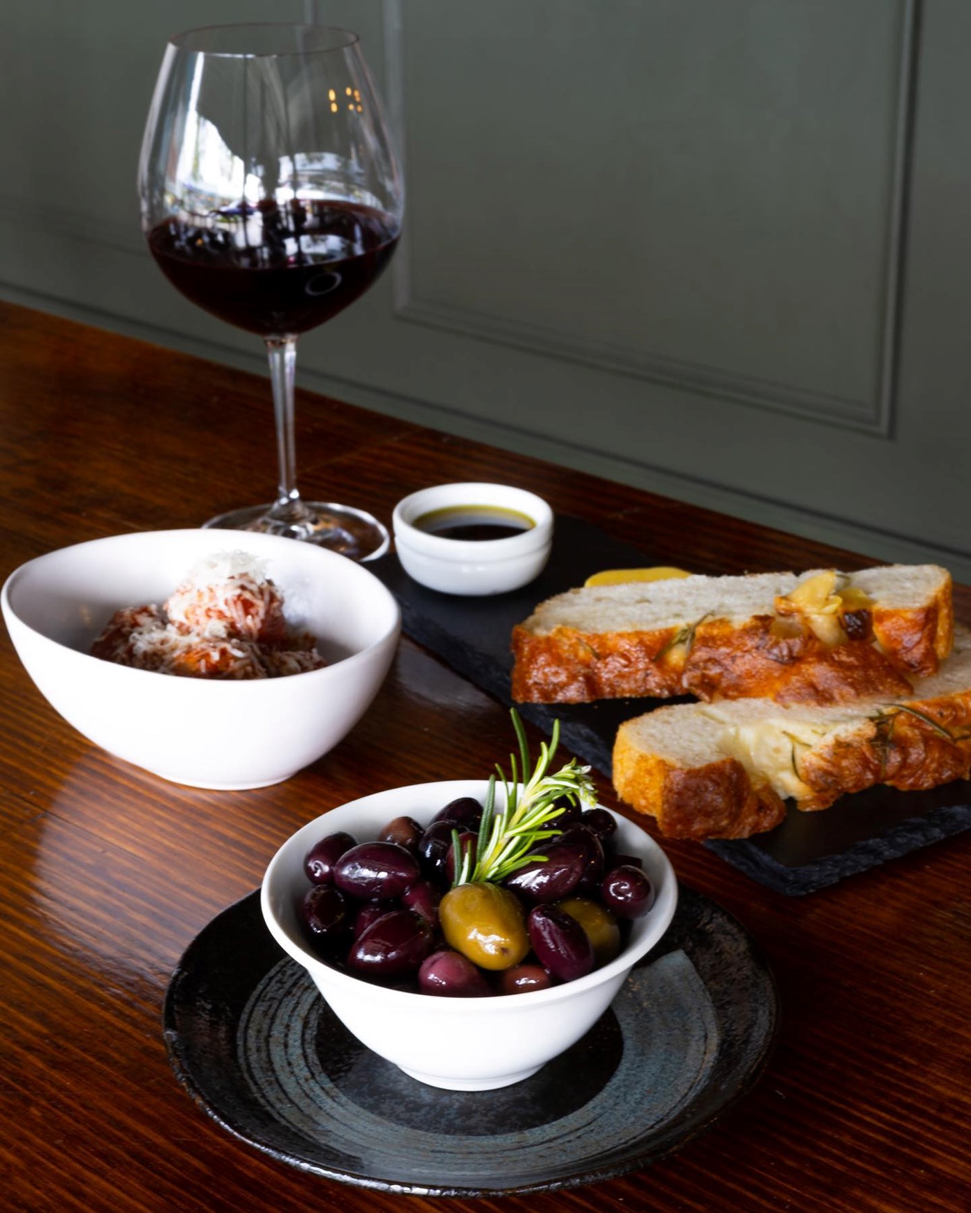 Olives, bread, arancini and wine on a table at Wine & Larder Bistro in Ashgrove, Brisbane