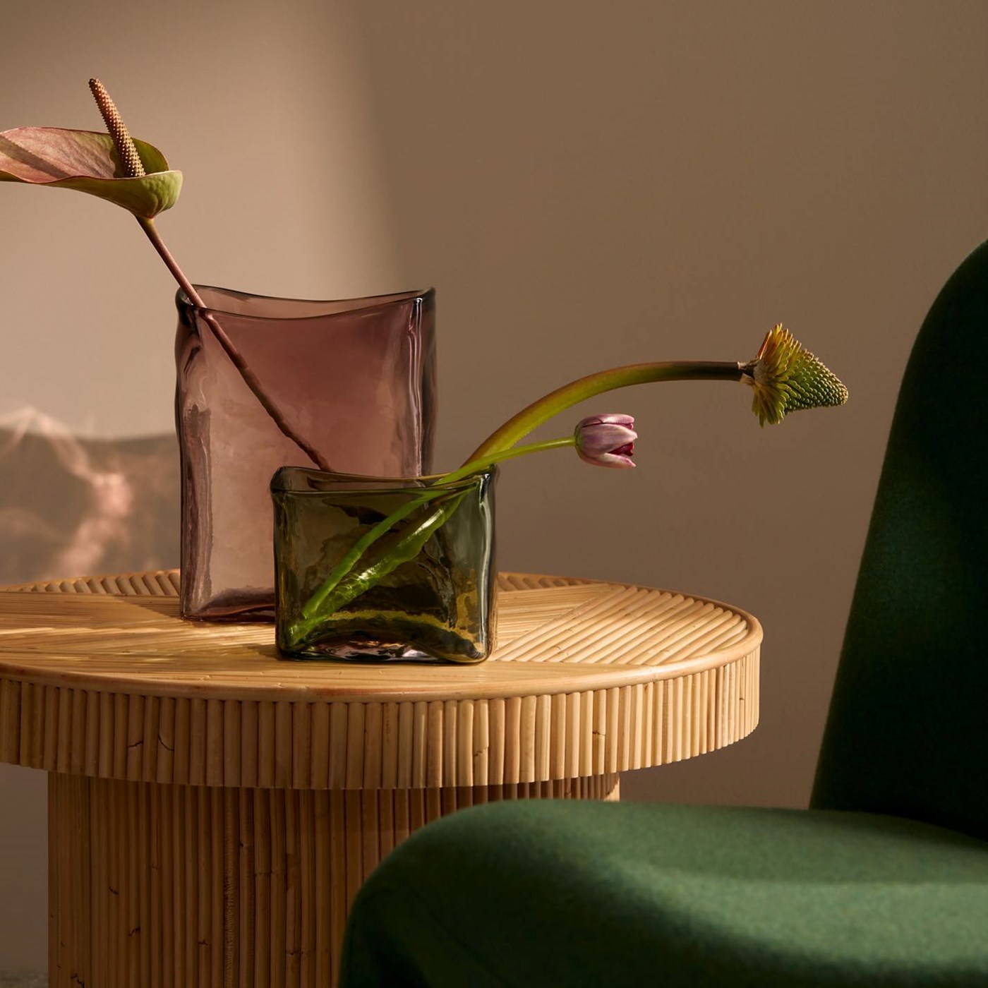 Two rectangular glass vases (one rose, one green) from Marmoset Found sitting on a circular wooden table 