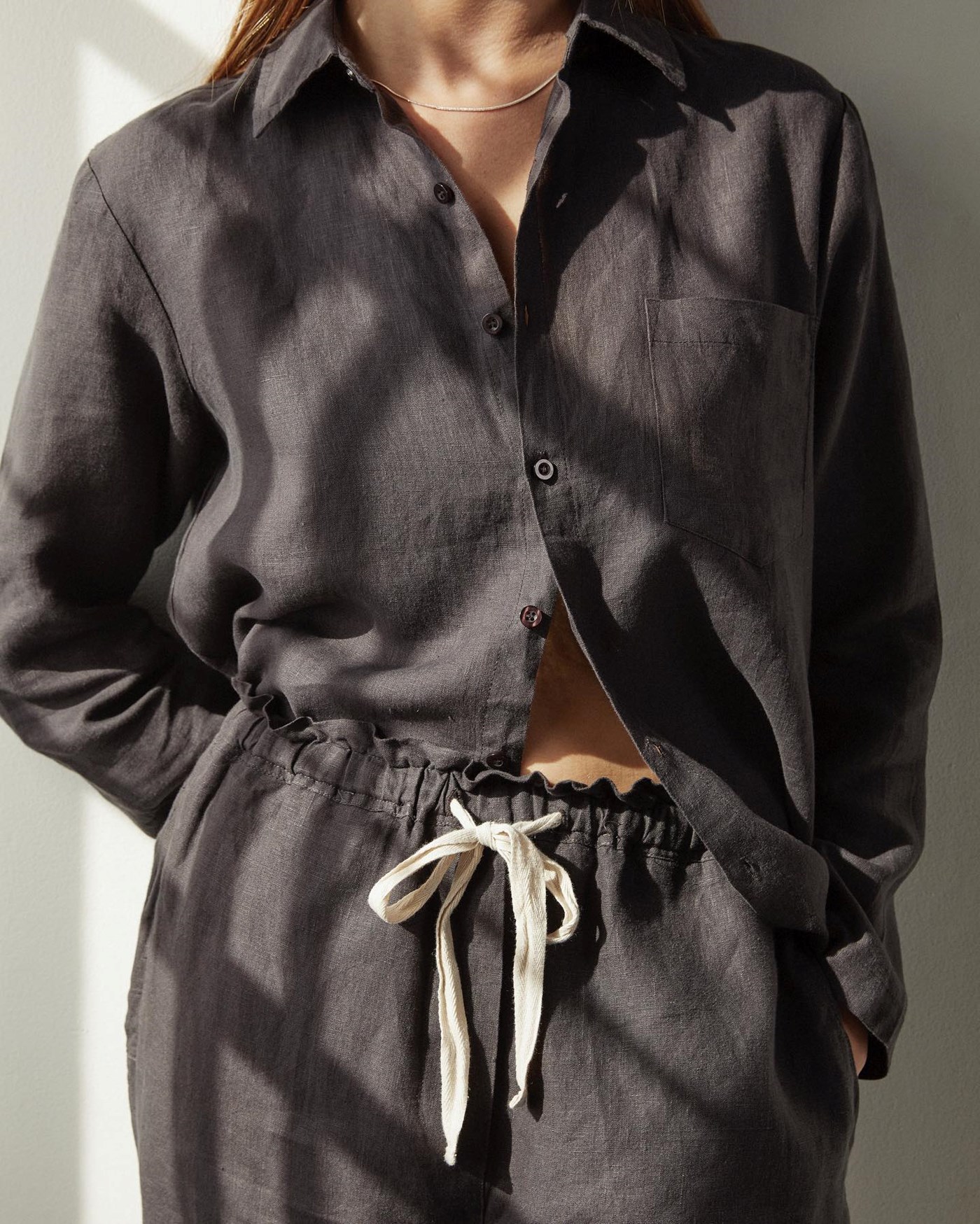 A woman wears a black pyjama set. 