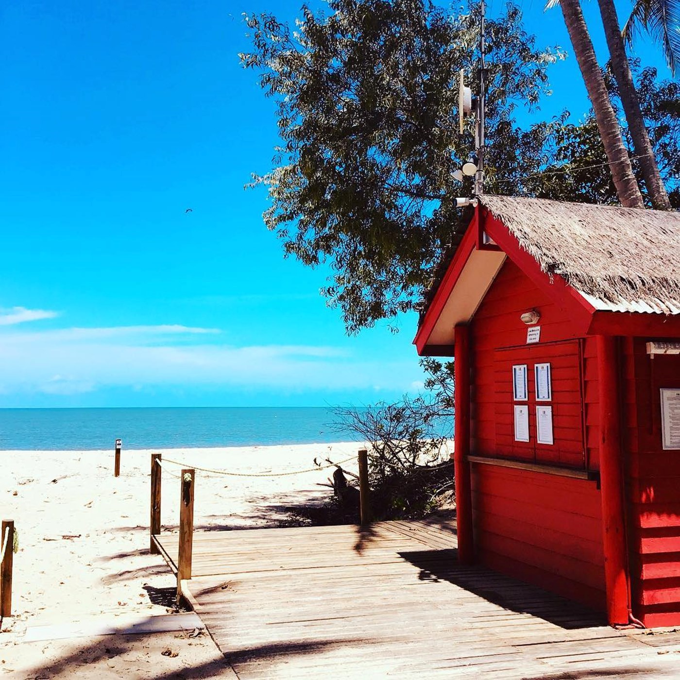 Red beach shack next to a boardwalk facing onto the beach