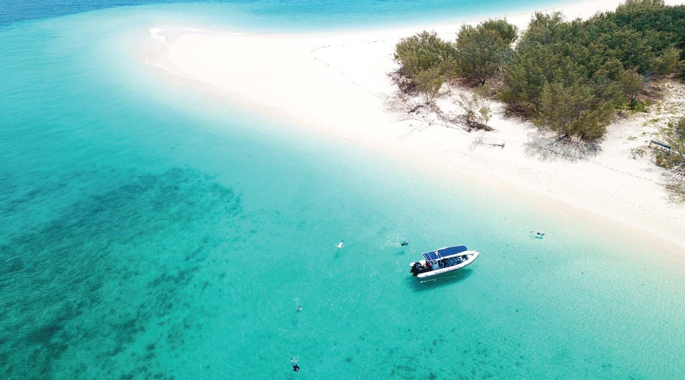 Bright blue waters and white sand with a single boat on Great Keppel Island. 