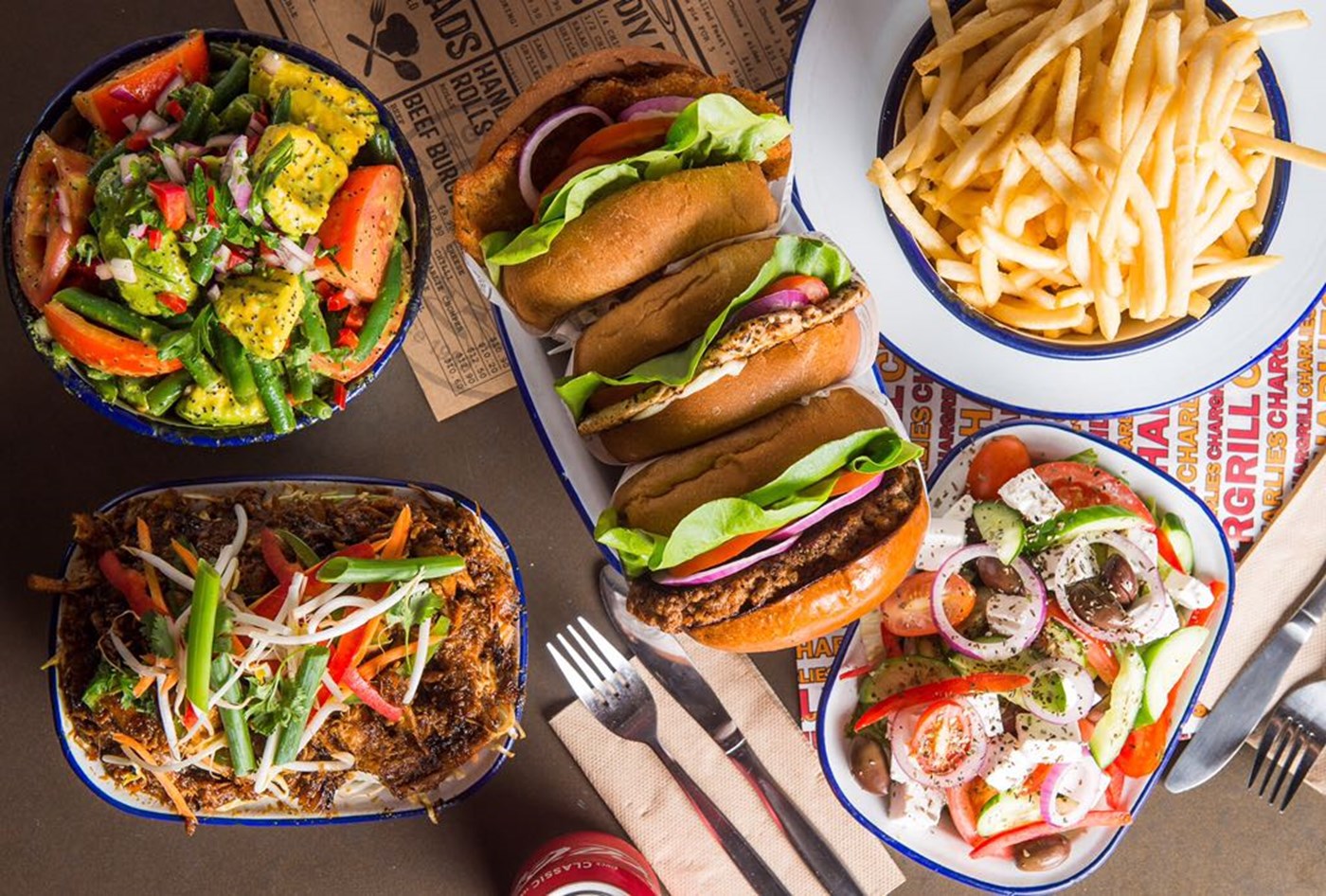 A top down photo of a spread of burgers, chips and salads from Chargrill Charlie's 