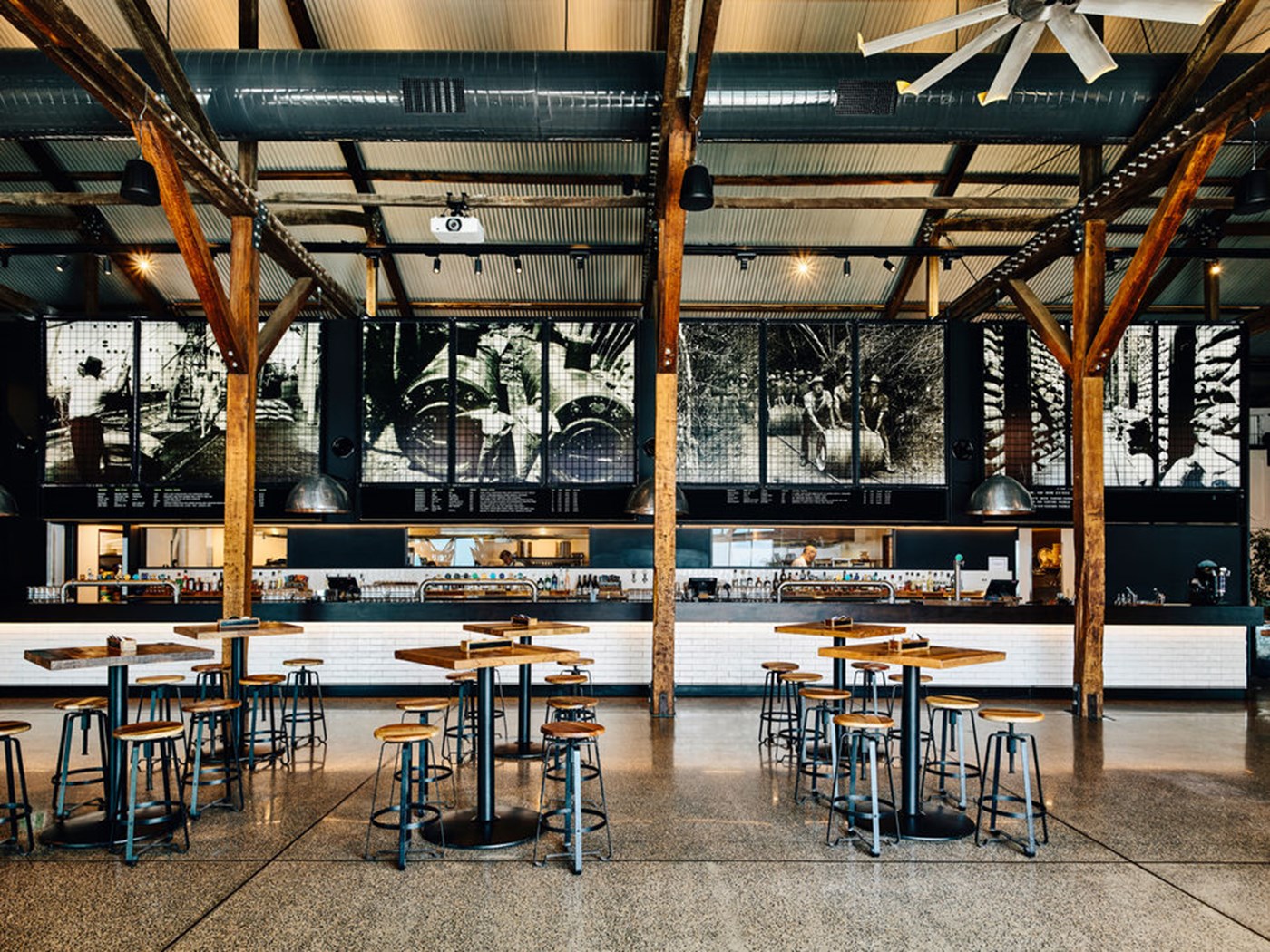 An industrial style brewery interior with brown tables and exposed wooden beams.