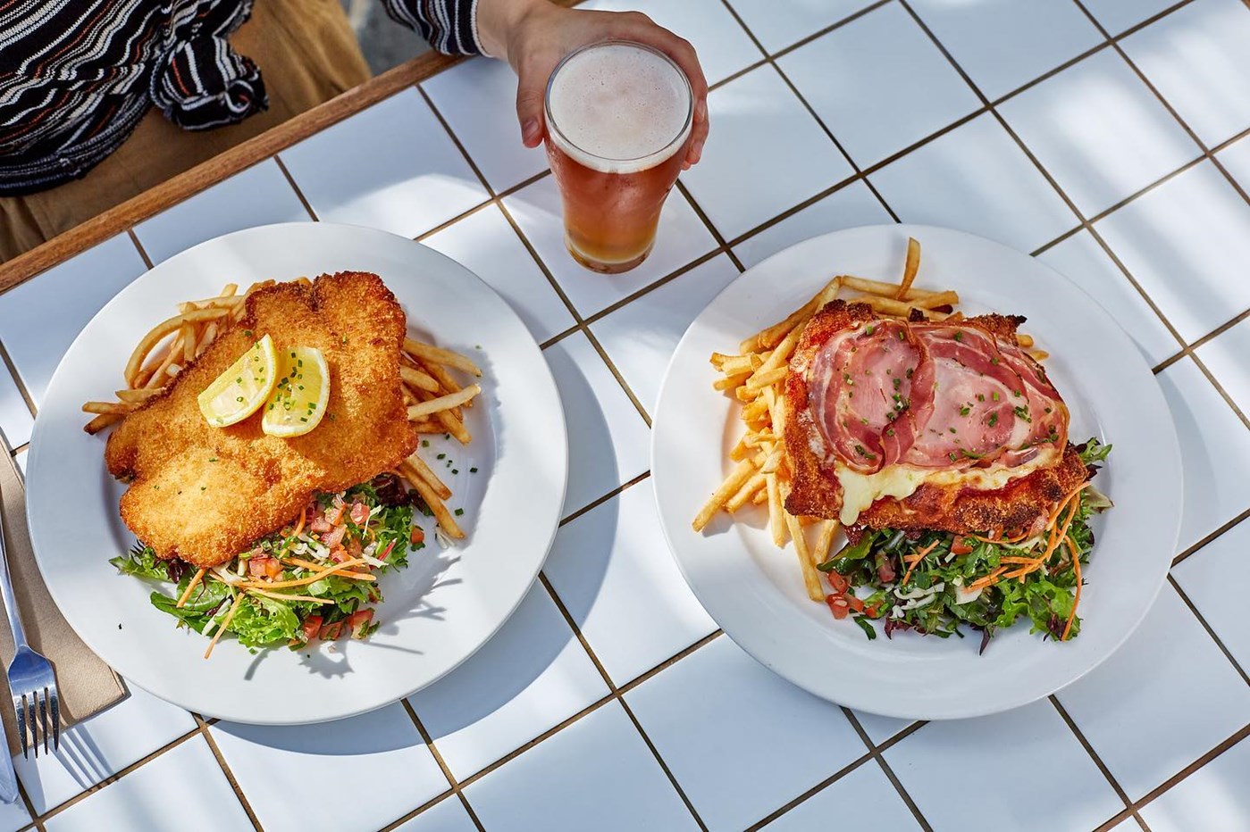 A Chicken schnitzel, chicken parmigiana and a beer against a tiled table at Beach Road Hotel 