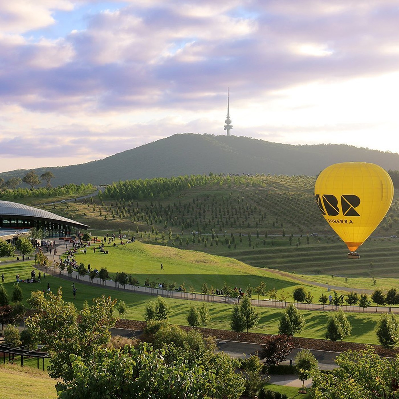 Landscape shot of National Arboretum Canberra Landscape with rolling green hills and a yellow hot air balloon