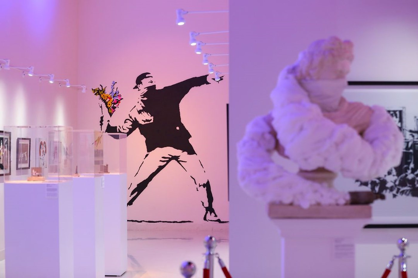A snap from the Art of Banksy exhibit featuring pink lighting and stencilled wall art 