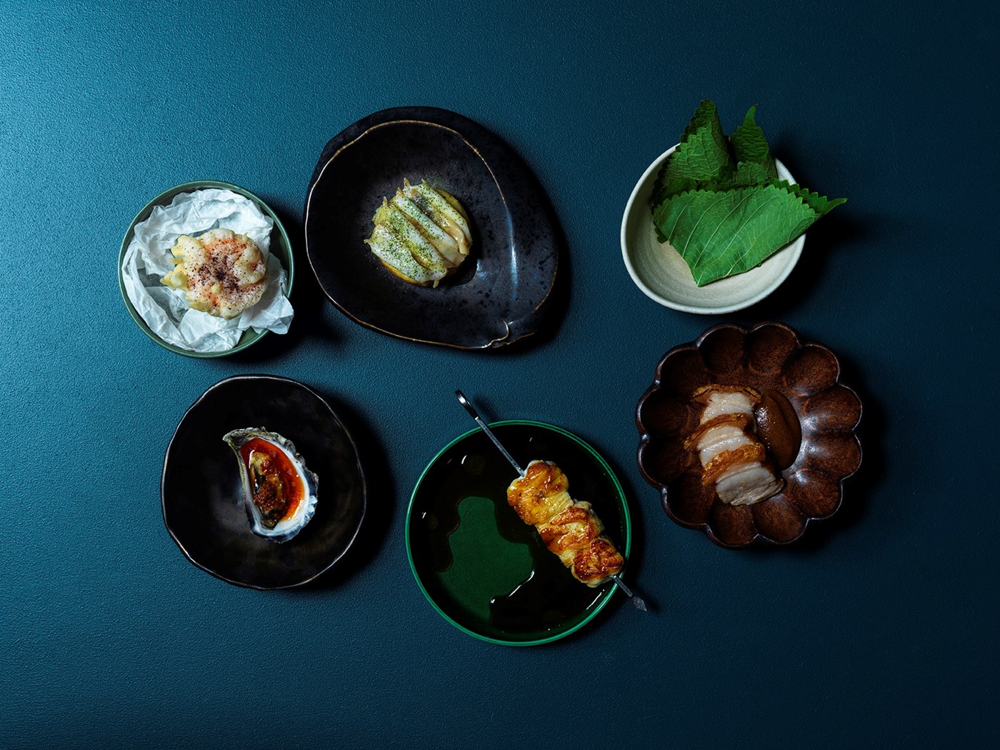 A selection of snack items in eclectic bowls against a vibrant blue background 