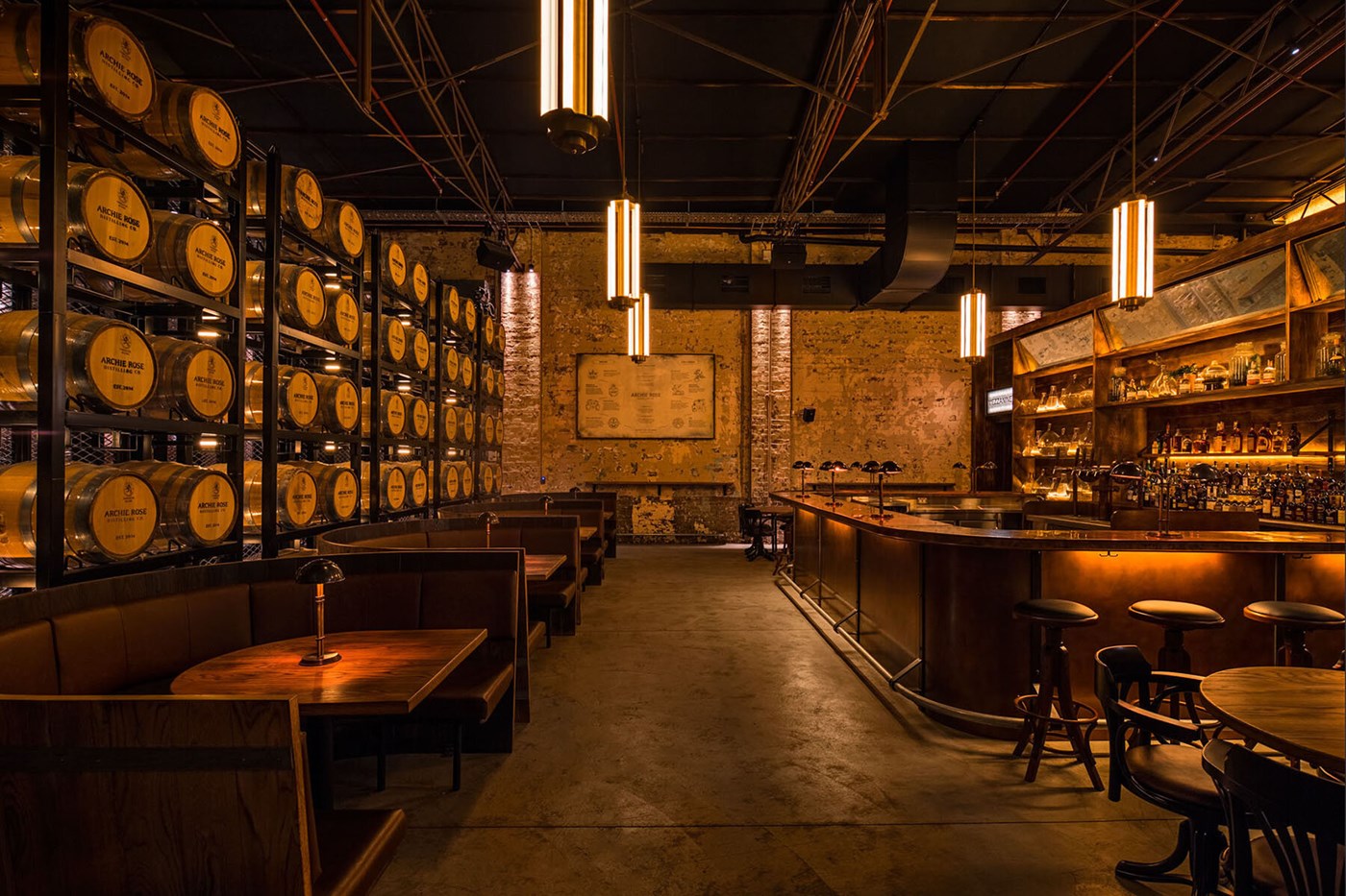 The moody interiors of the bar at Archie Rose Sydney with one wall lined with barrels 