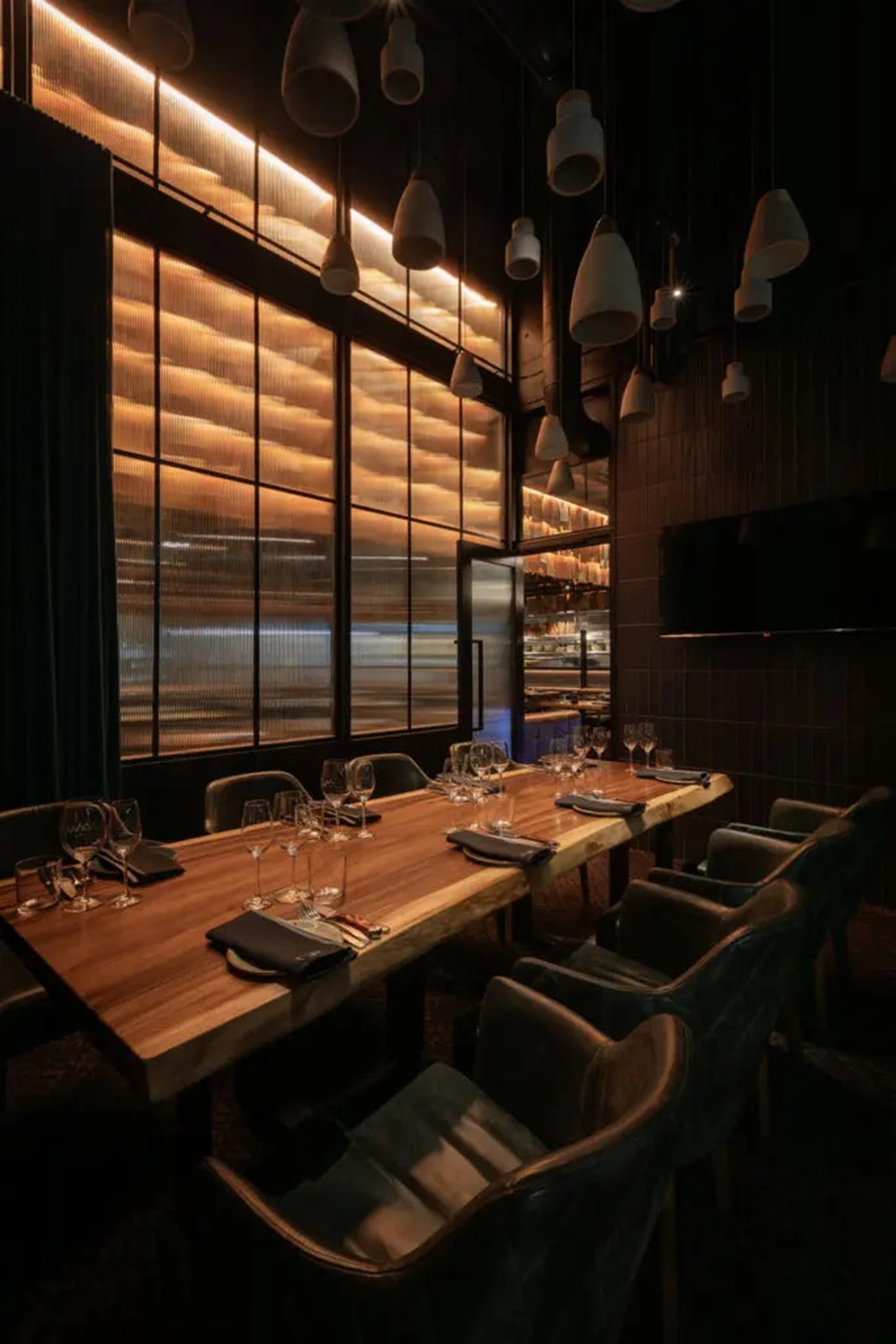 A very dark and moody private dining room with a table set for six 