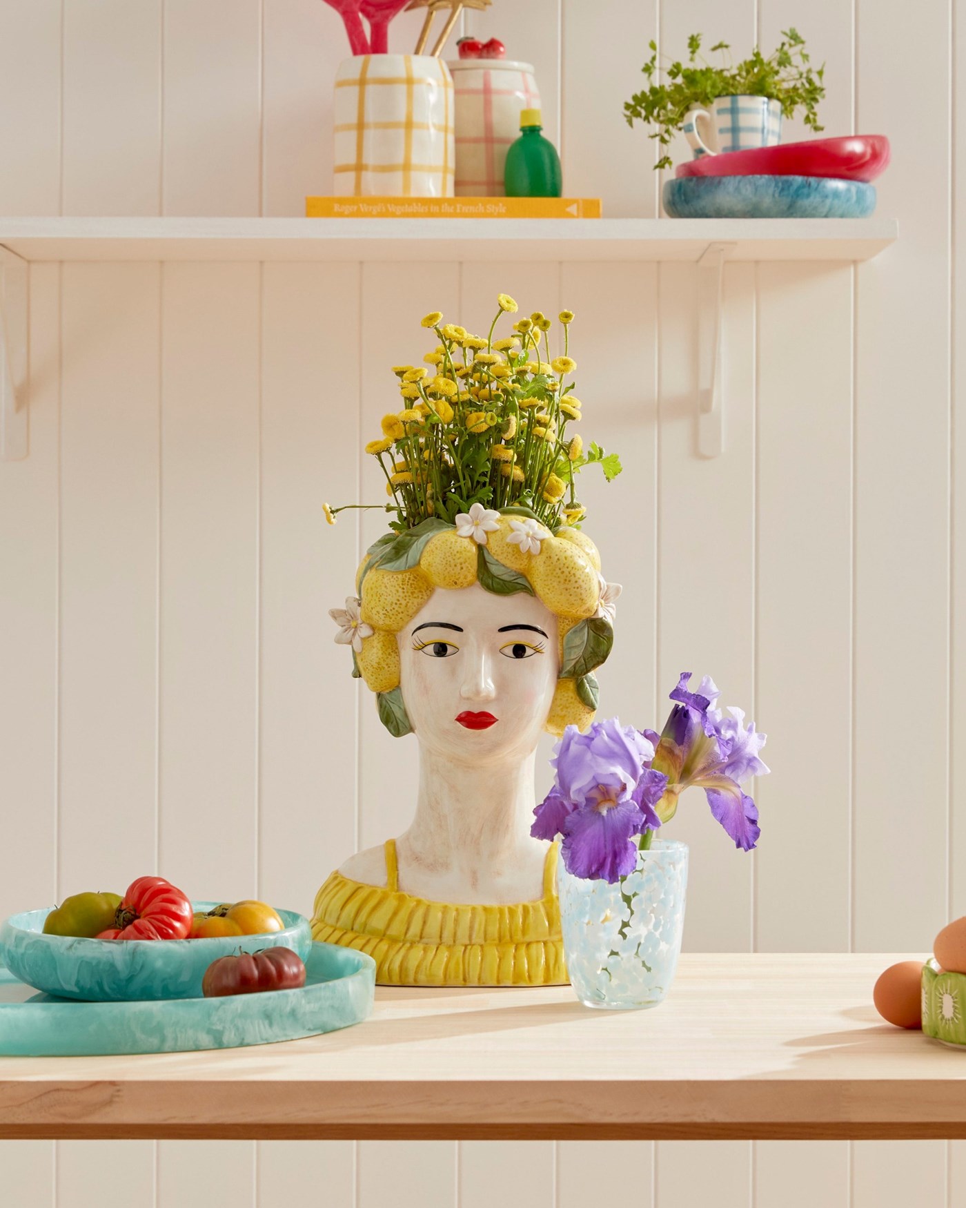 A panelled kitchen wall with a women with a lemon headdress made from ceramic and holding a bunch of yellow flowers 
