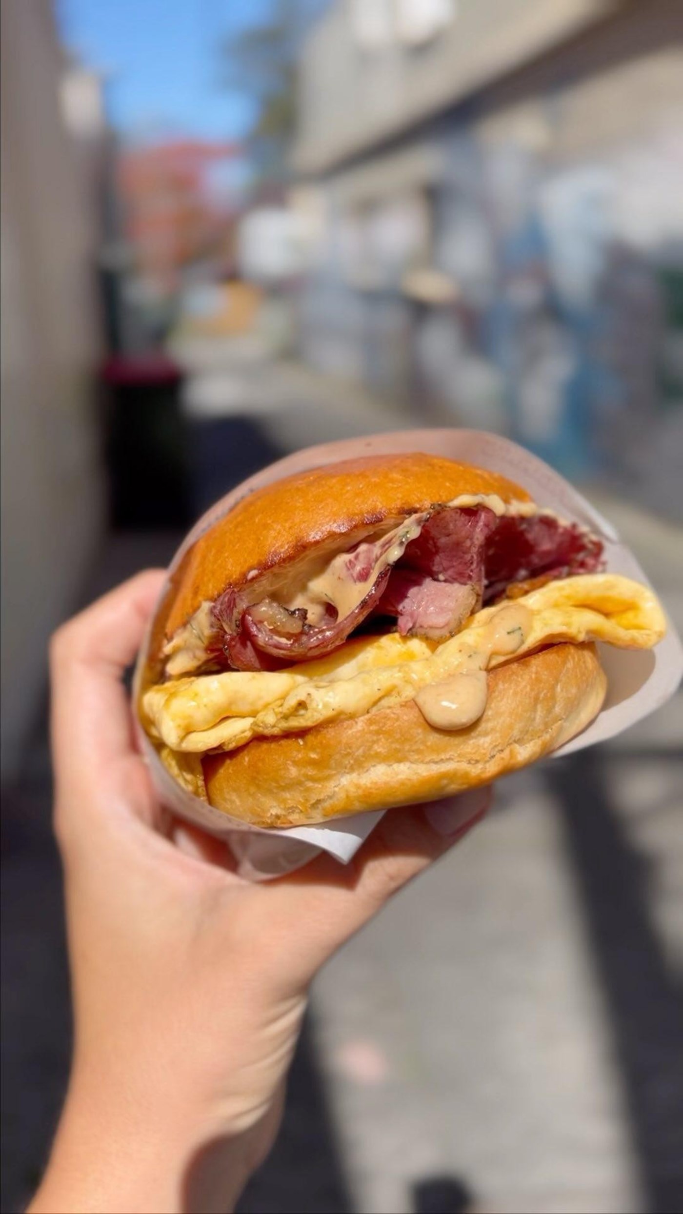 a hand holding up a Breakfast Sammy from Frank's Deli Waverley Sydney