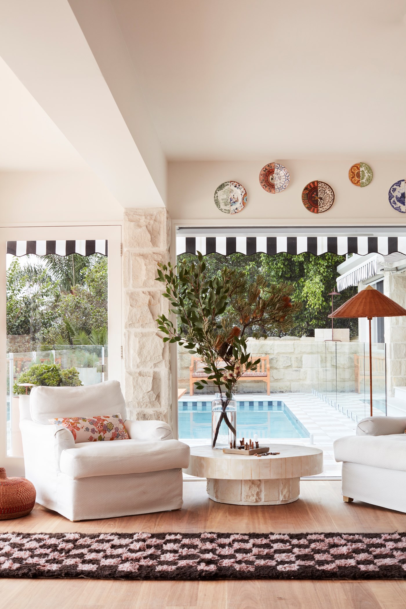 Two sitting chairs in the living room of La Palma are framed by a textured rug and a pool in the background.