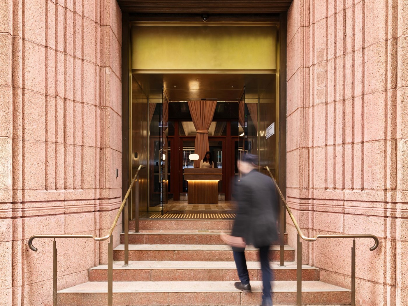 An opulent pink marble entrance with a blurred figure walking up the stairs 