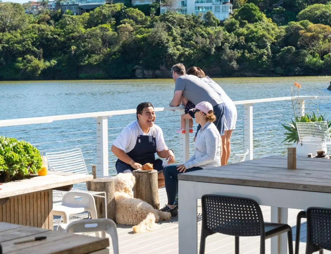 A chef patting a dog in the outdoor dining area of Navy Bear 