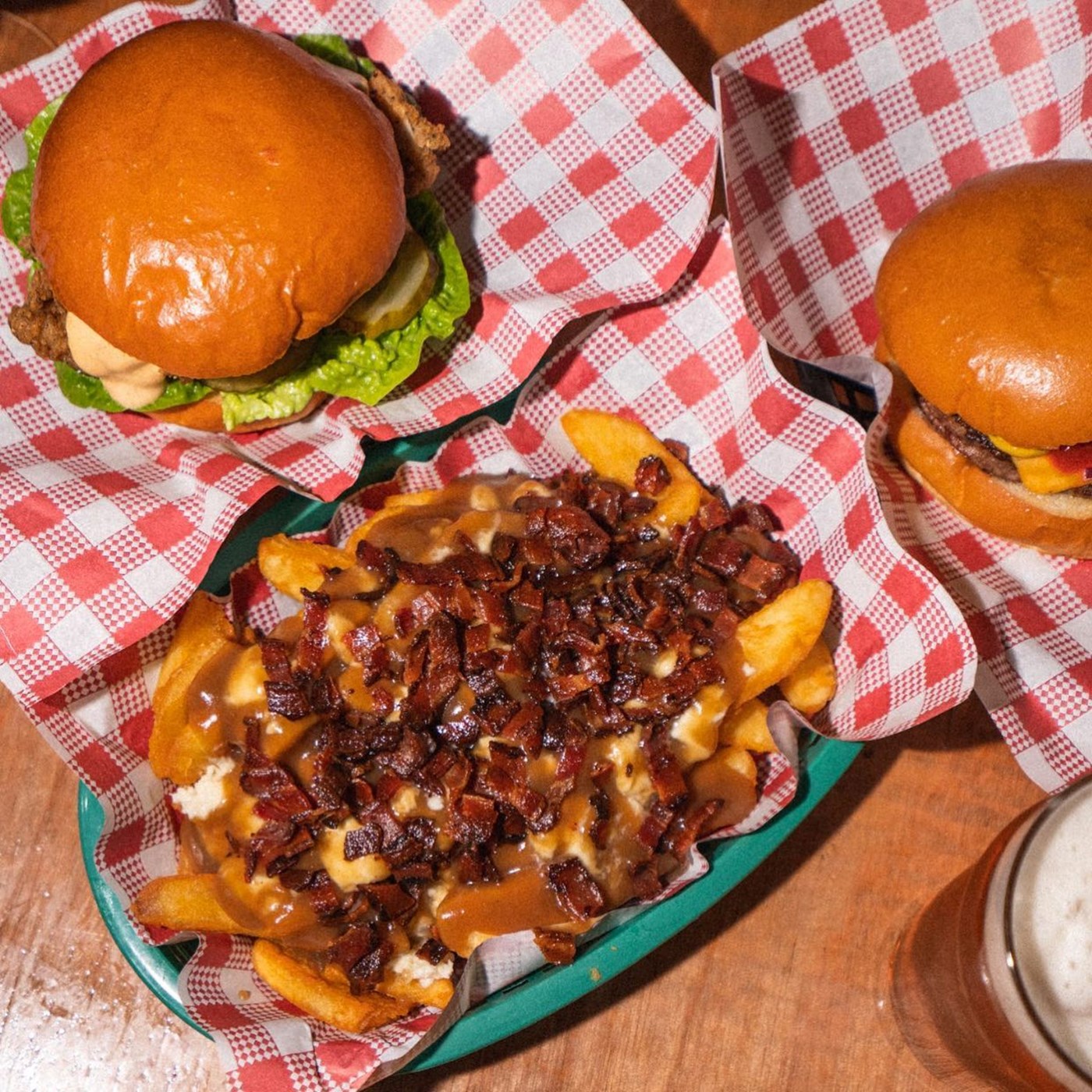 an overexposed image of poutine and burgers on red chequered paper at Stuffed Beaver 