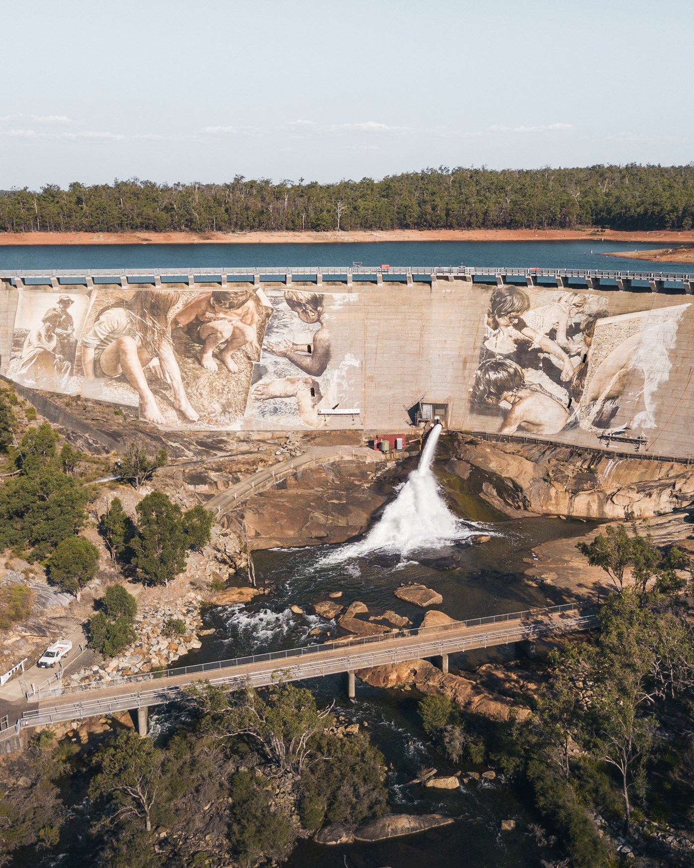 A large mural is painted on the dam walls as large amounts of water gushes out.