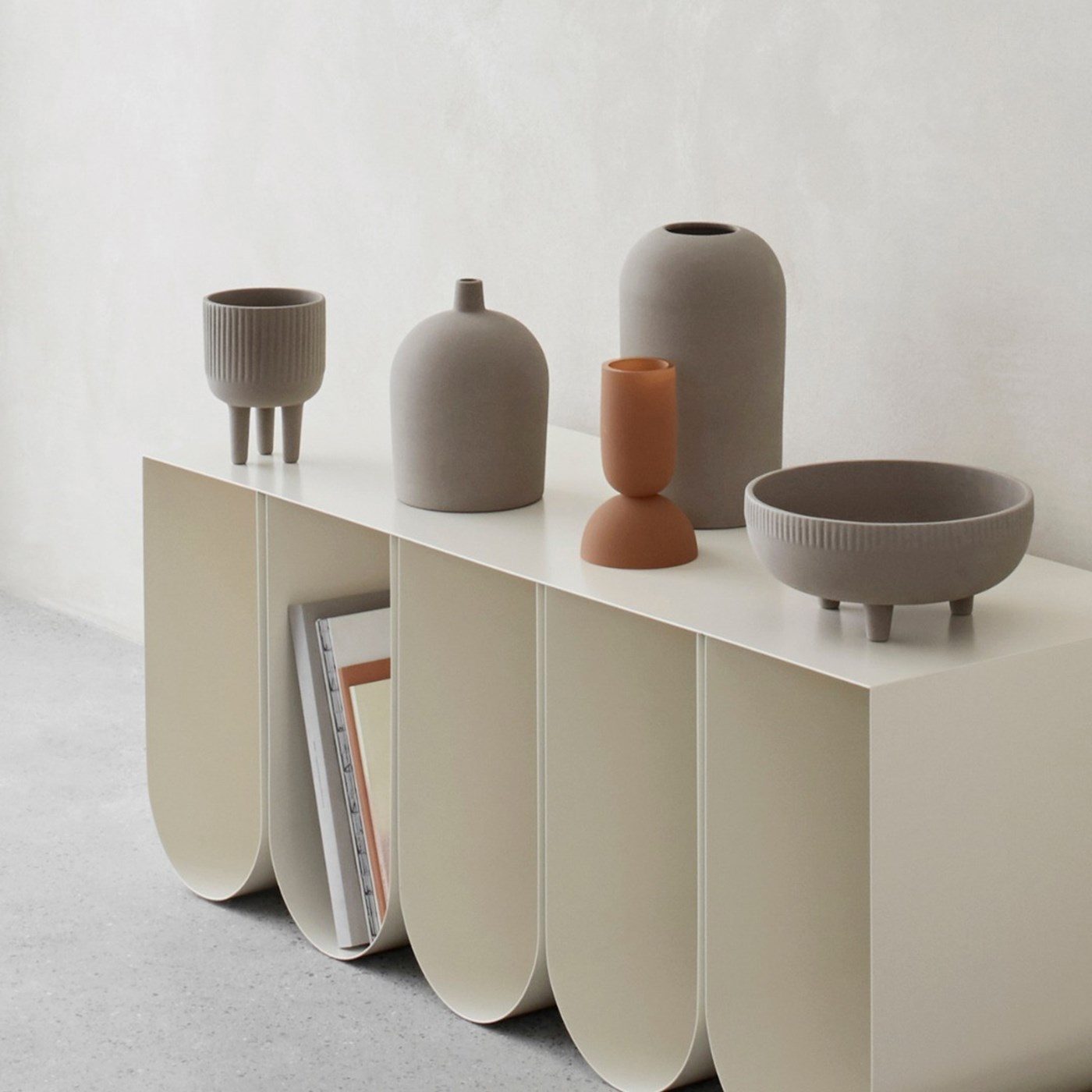 Minimalist grey and brown ceramic vessels atop a modern metal side board 