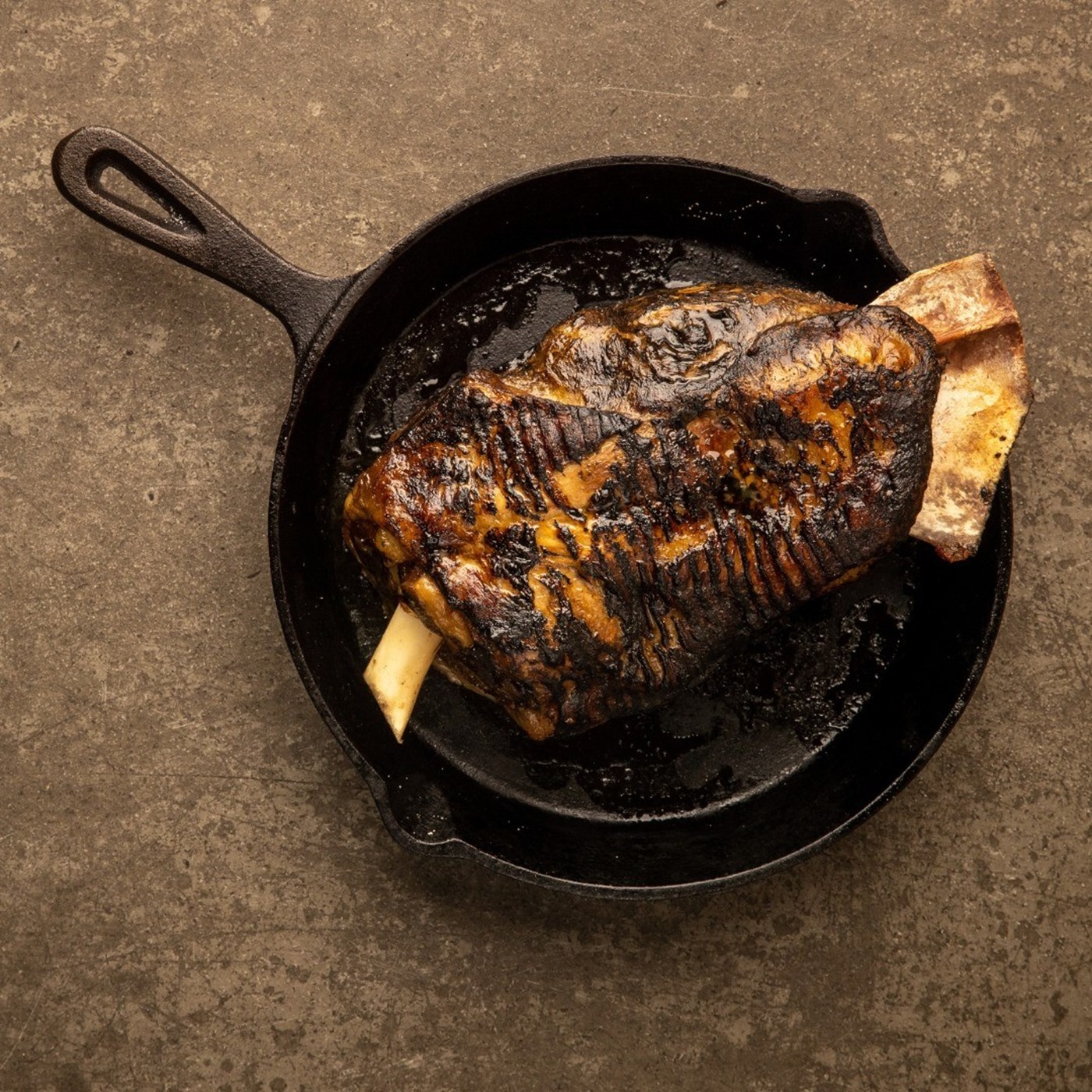 A skillet with a roast leg of lamb in it 