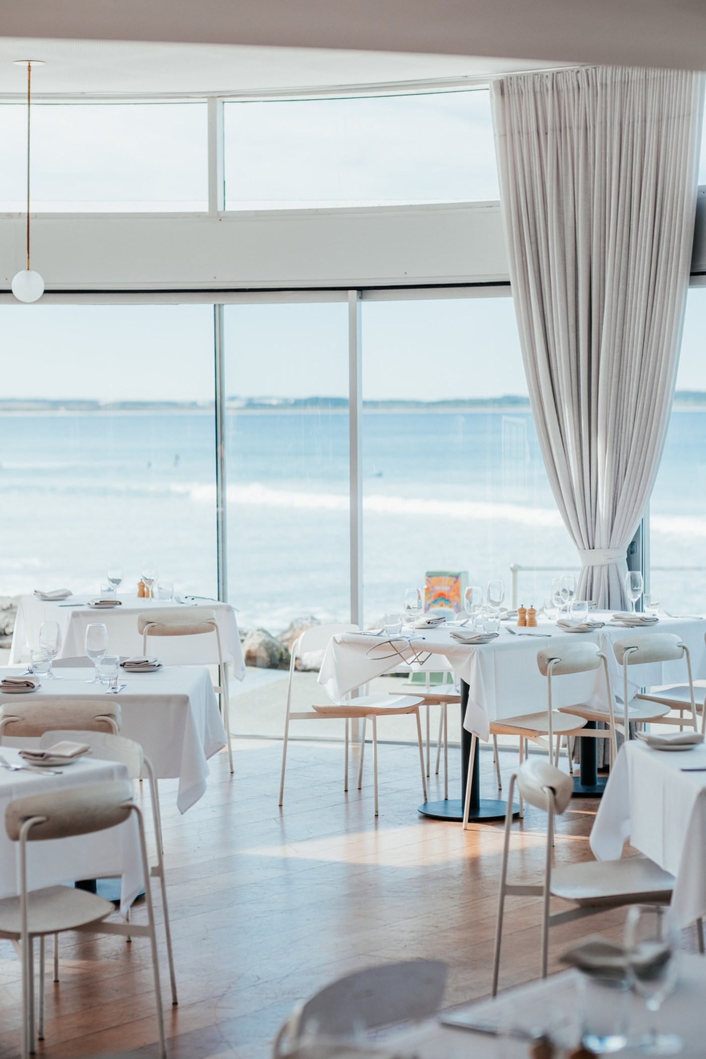 The light and bright dining room at sealevel featuring floor to ceiling windows and panoramic ocean views. 