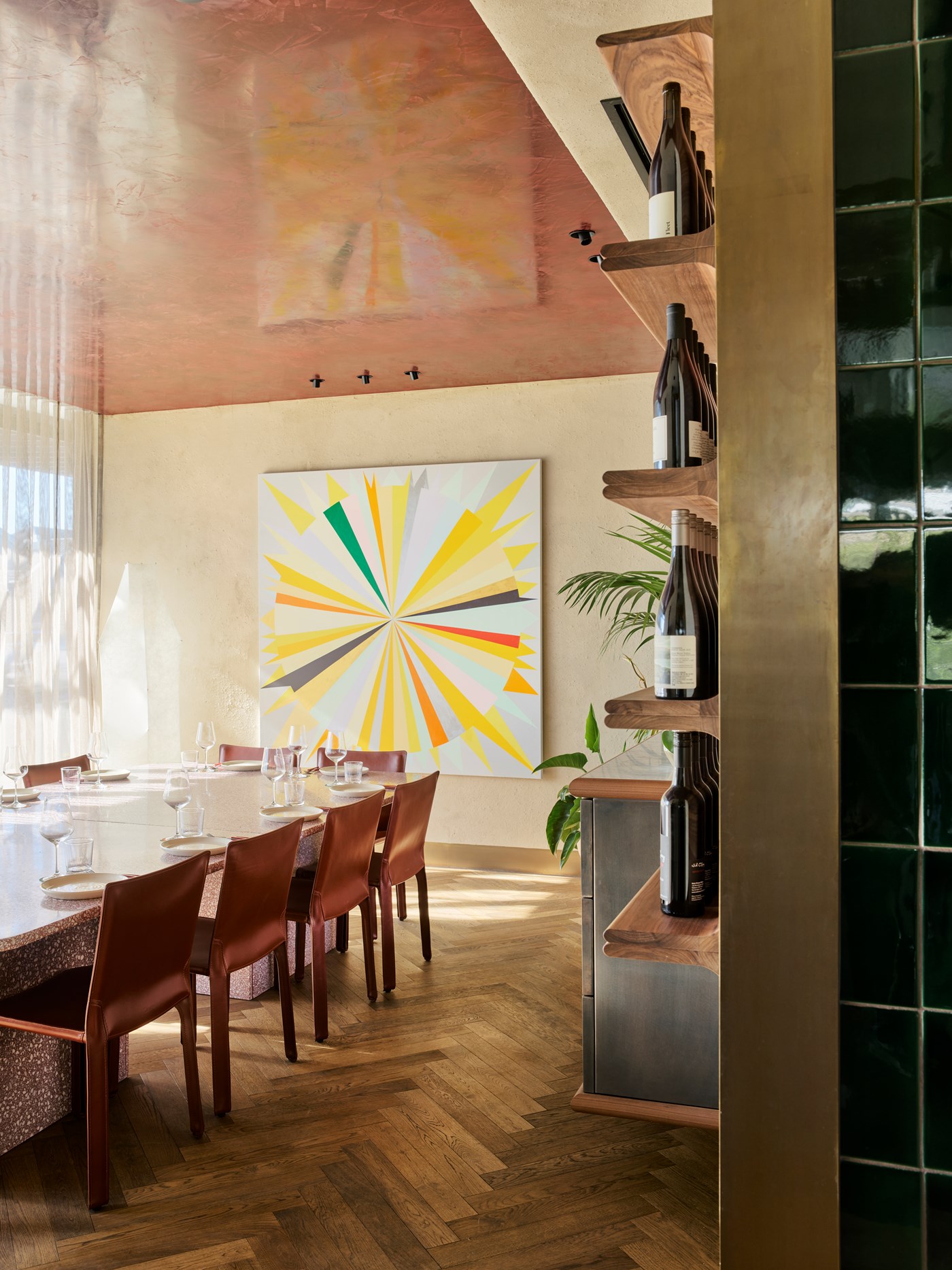 A stylish dining room with herringbone floors, leather chairs and a bright artwork against the wall 