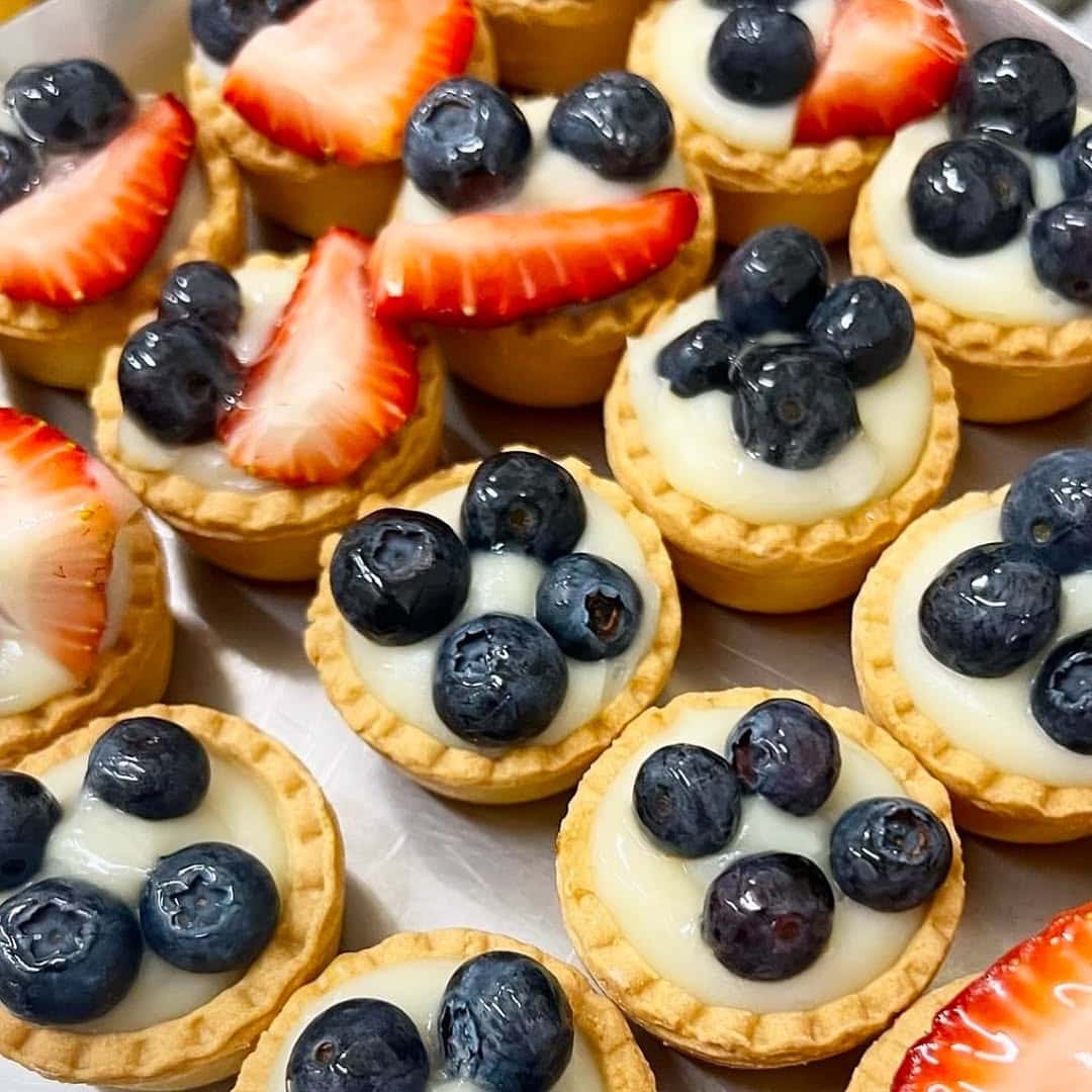 An array of mini tarts with strawberries and blueberries. 