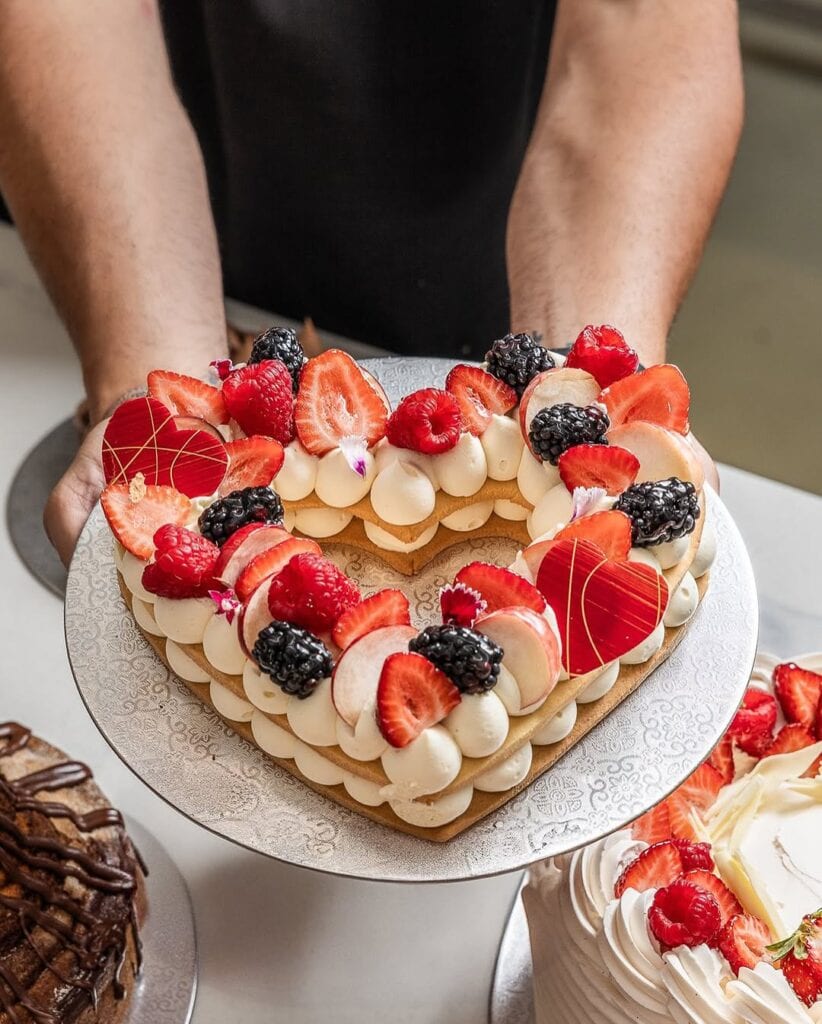 A person holds a heart-shaped cake.