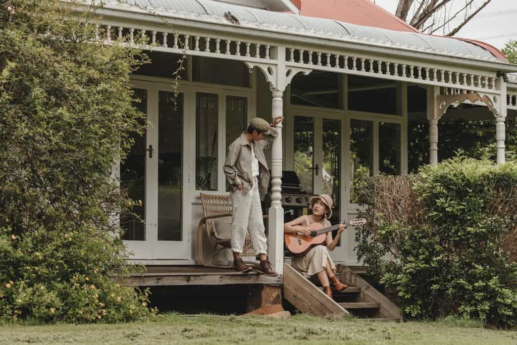 People playing guitar on the veranda of the historic Berry Hill Riverfront Homestead. 