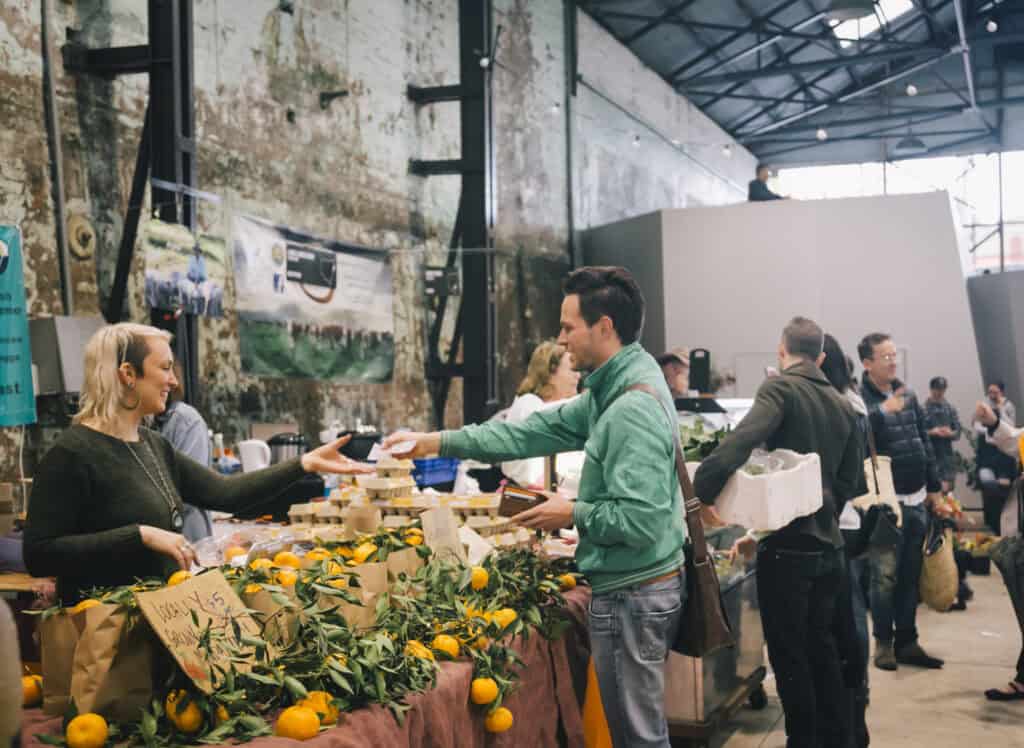 A man purchasing oranges at Carriageworks Farmers Markets in Redfern.