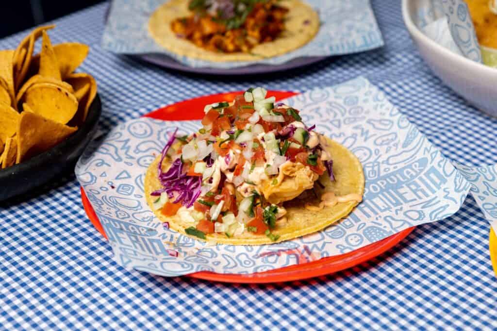 A plate of tacos from La Popular Taqueria in Adelaide, sitting atop a blue and white check table cloth.
