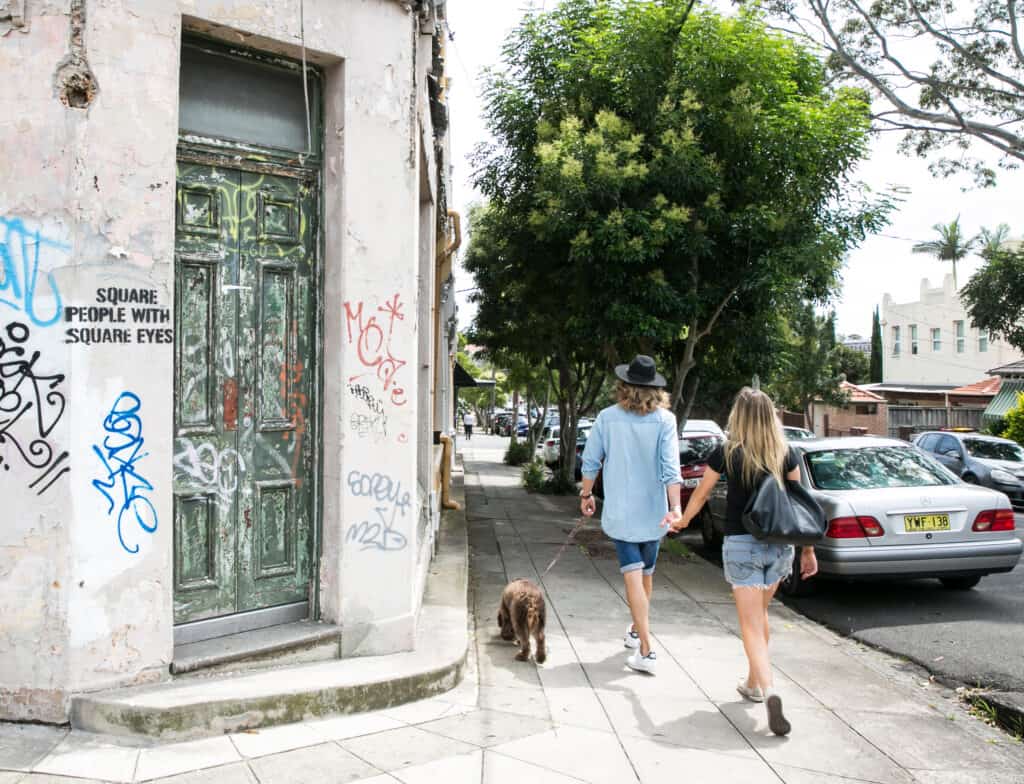 A couple walk down the street with their dog.