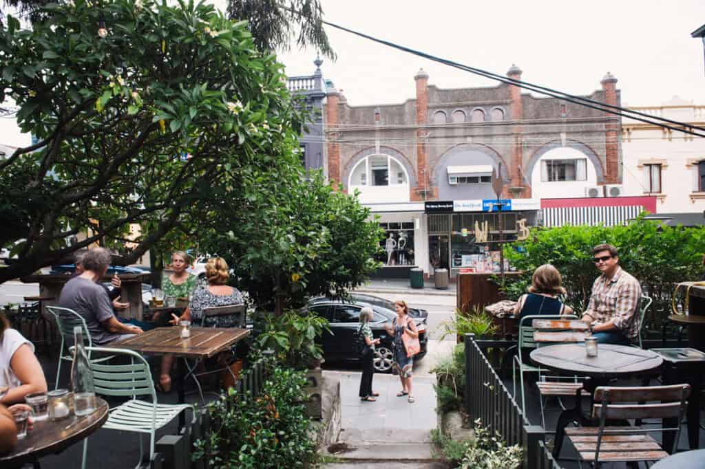 People walk into a leafy cafe in Balmain.