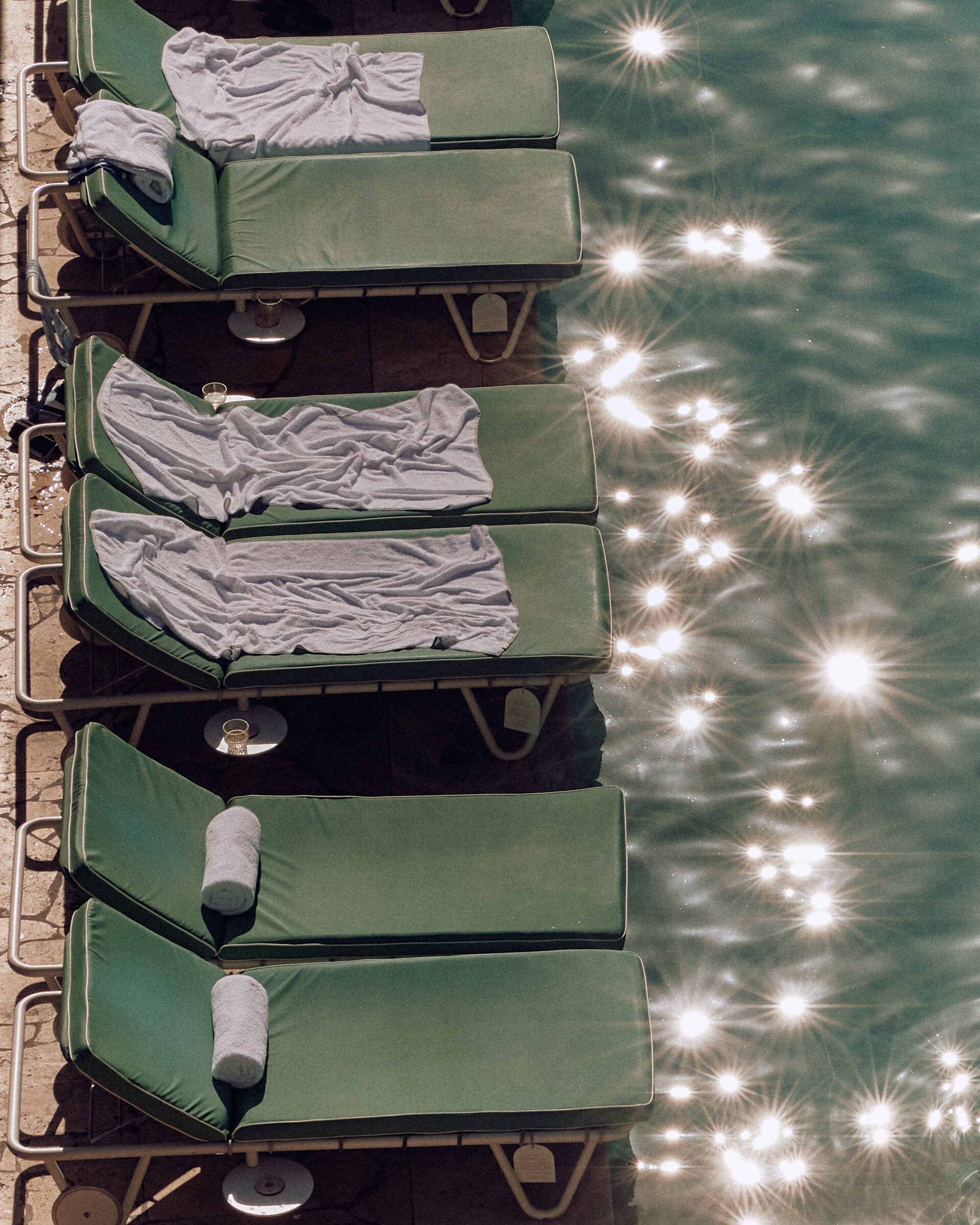 Lilo chairs (some with towels) by a glittering hotel pool.