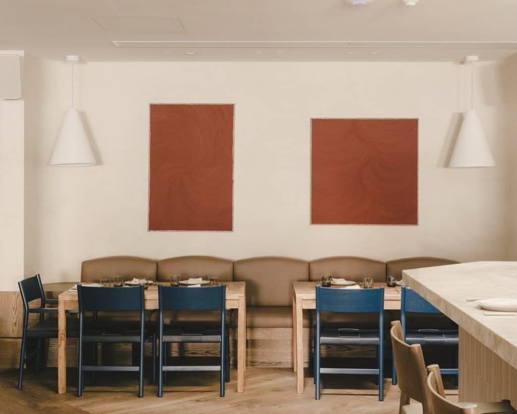 The minimalist dining room at white horse in surry hills, featuring terracotta artworks and blue and latte seating.