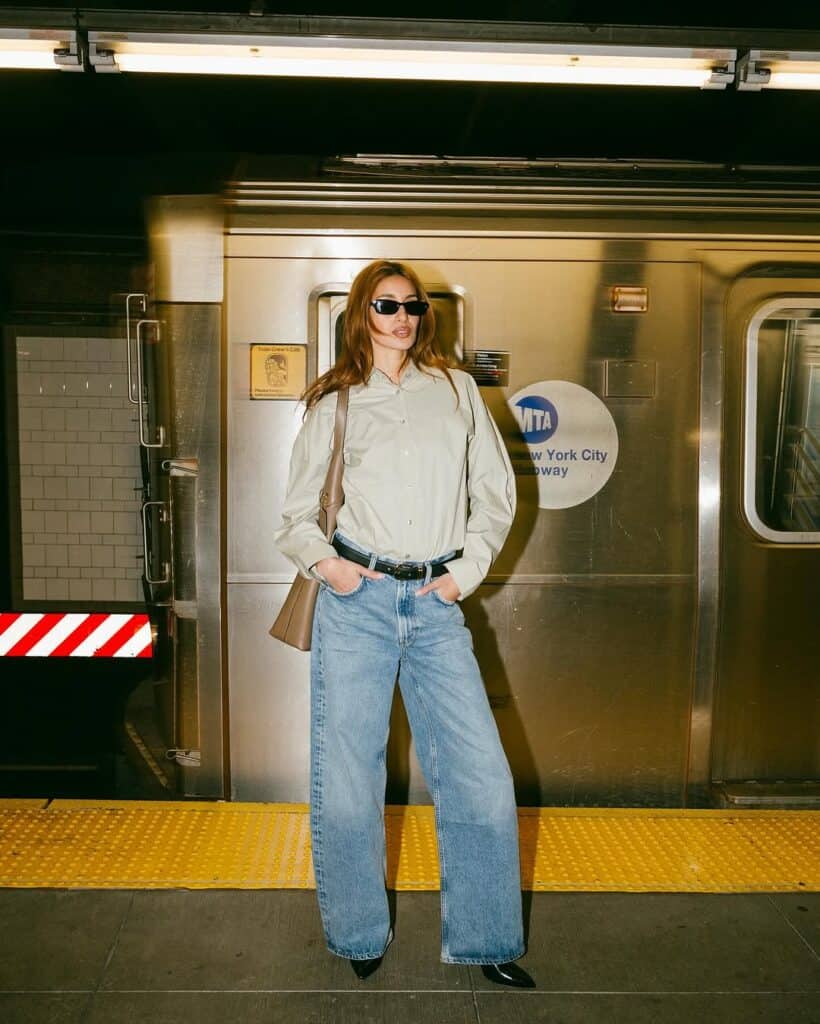 A woman on the New York subway wears a pair of low-curve jeans and a white top.