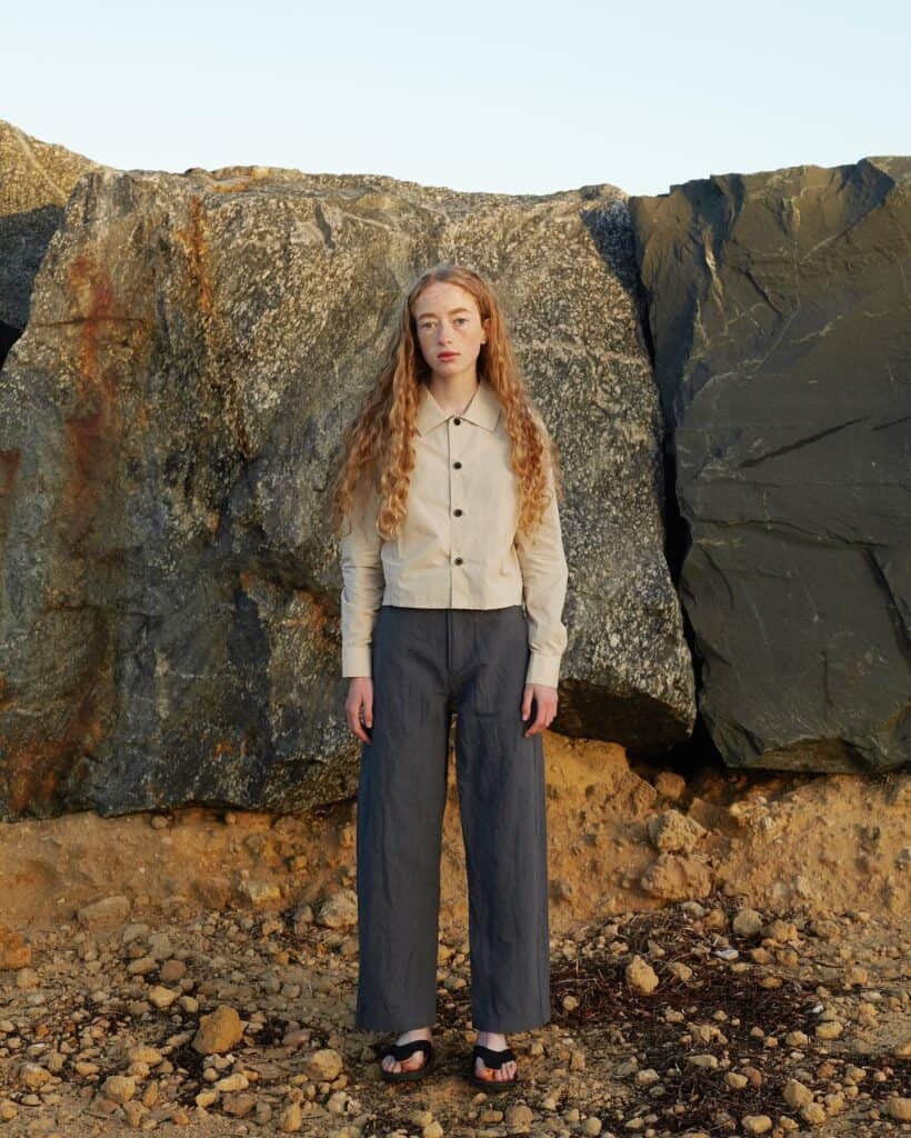 Woman standing in front of rock wearing MAN-TLE