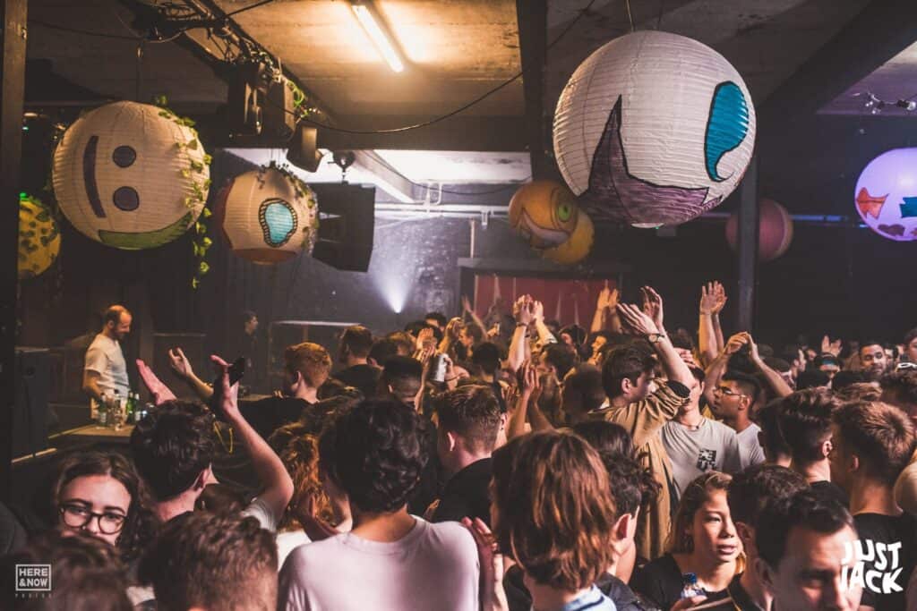 People dance in front of a DJ in a tent.