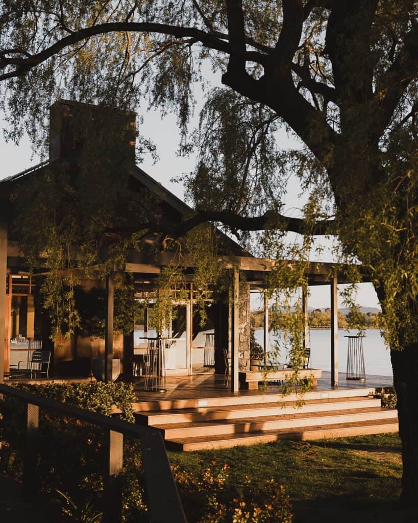 A tree-lined restaurant overlooks a lake.