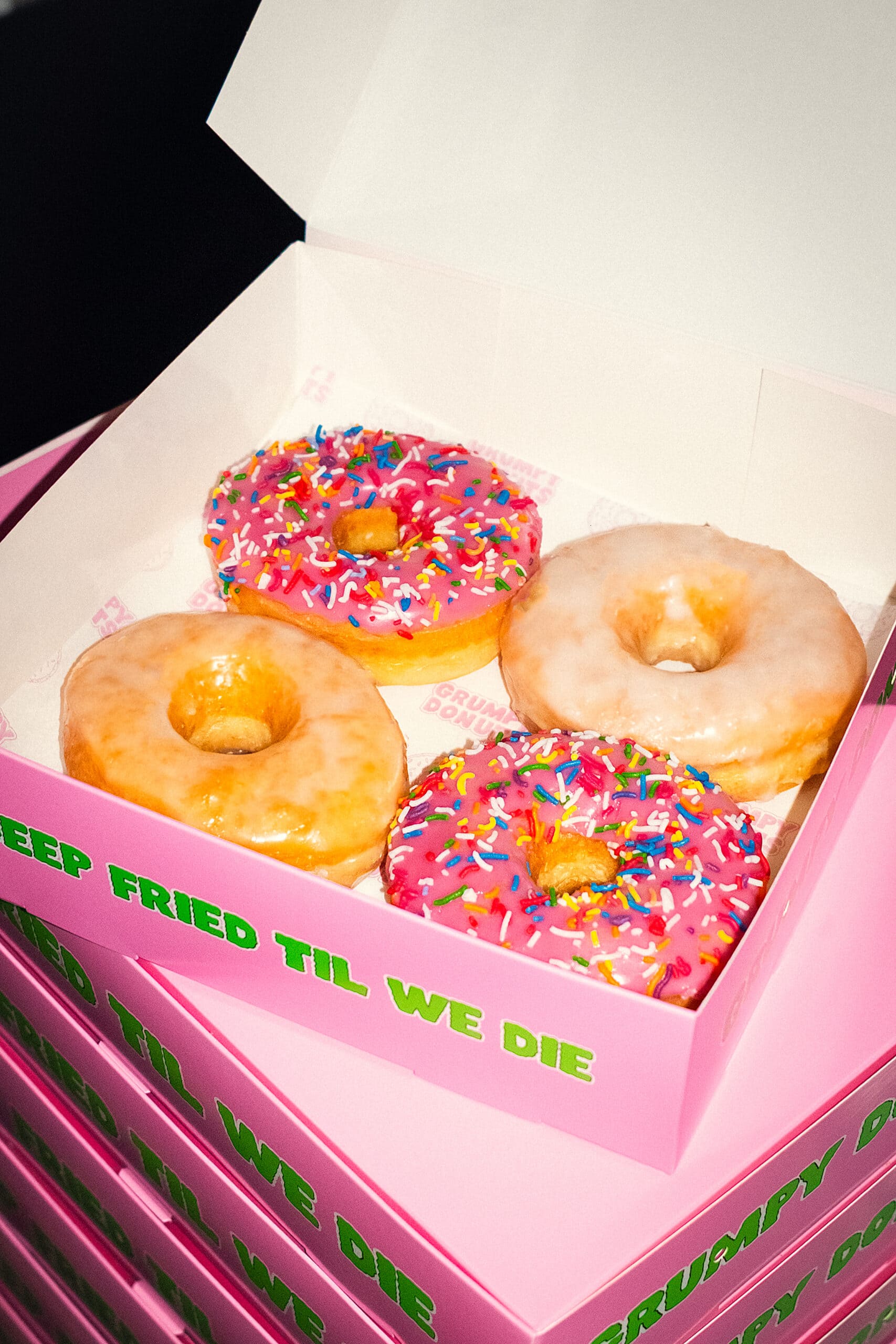 Four glazed and pink sprinkle donuts in branded pink box at Grumpy Donuts St Peters Sydney
