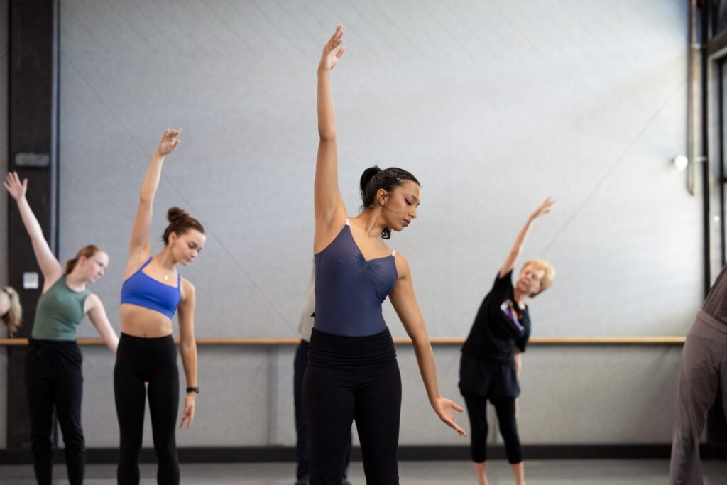 A group of women stand with one arm in the air