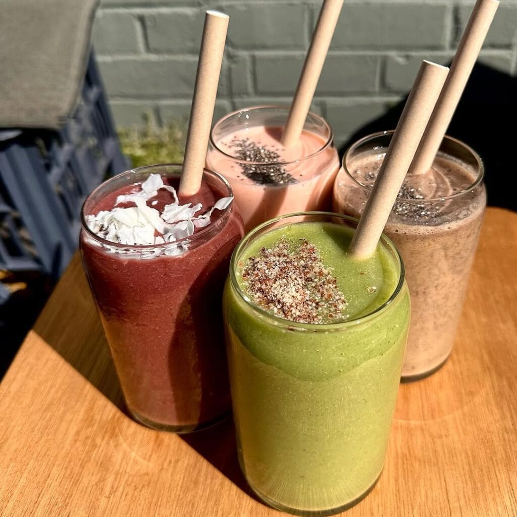 Four colourful smoothies on a wooden table.