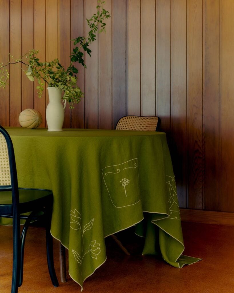 A table set with a vibrant green tablecloth at in bed store. 