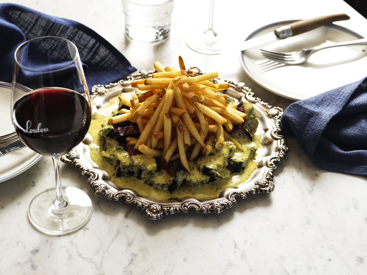 A stack of steak frittes atop a silver platter from loulou's cbd venue.