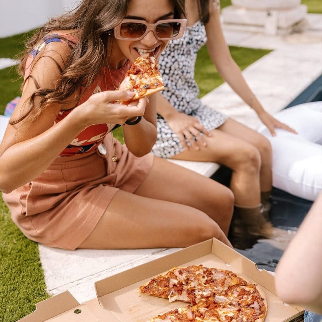 Woman biting into pizza from Crust