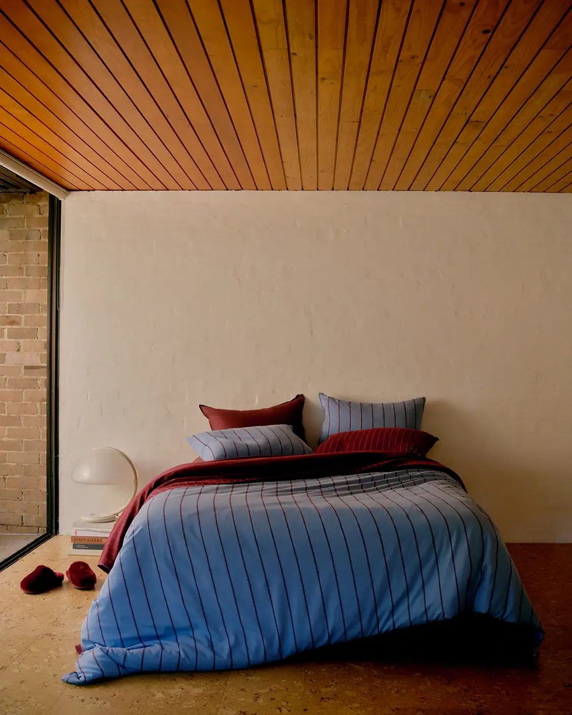 A bed fitted with striped bedding from Hommey