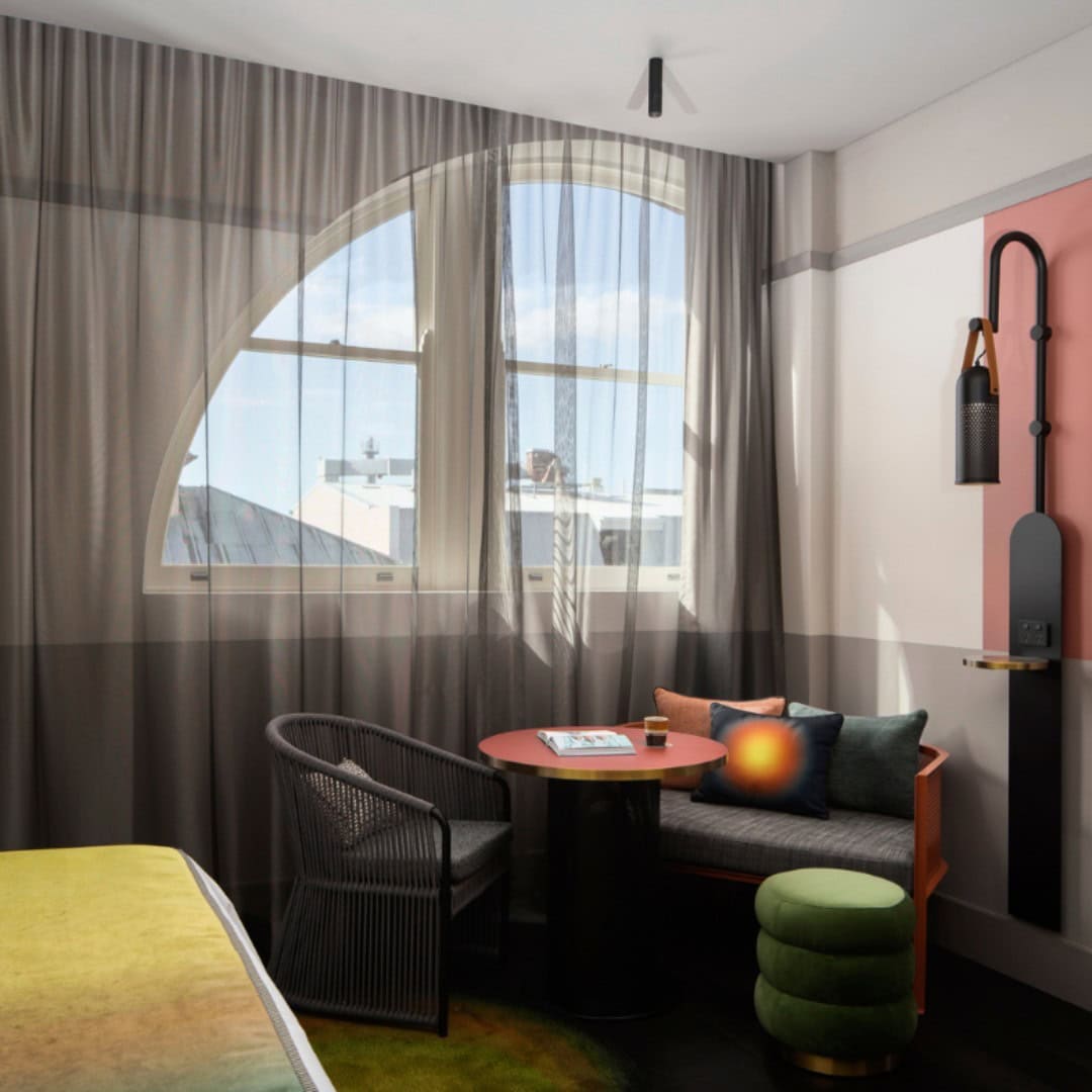 One of the rooms at QT Newcastle with light filtering in through the sheer curtains.
