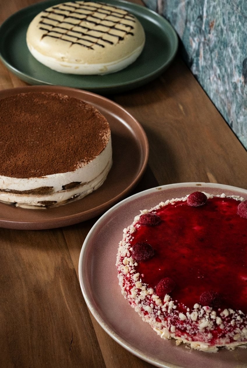 Three limited-edition semifreddo cakes including pistachio tiramisu and raspberry cheesecake on plates at Rivareno Gelato Sydney